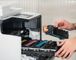 Businessman Fixing Cartridge In Printer Machine At Office Midsection of young businessman fixing cartridge in printer machine at office